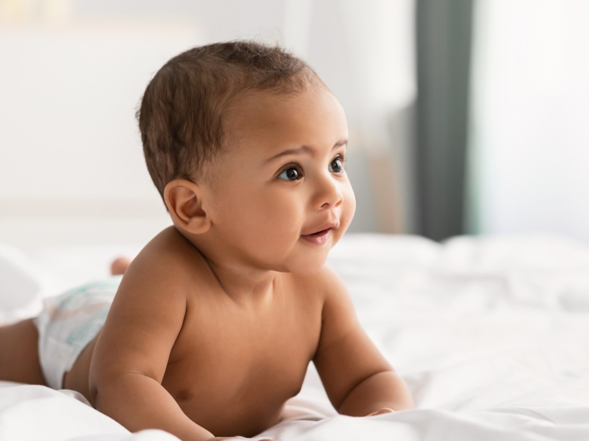 Baby auf Bett, dass sich mit den Händen abstützt