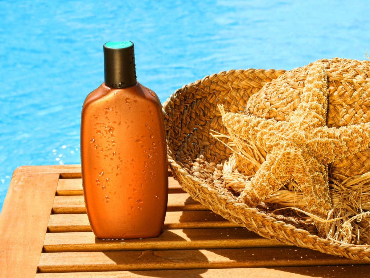 Flasche mit Sonnencreme vor einem Pool.