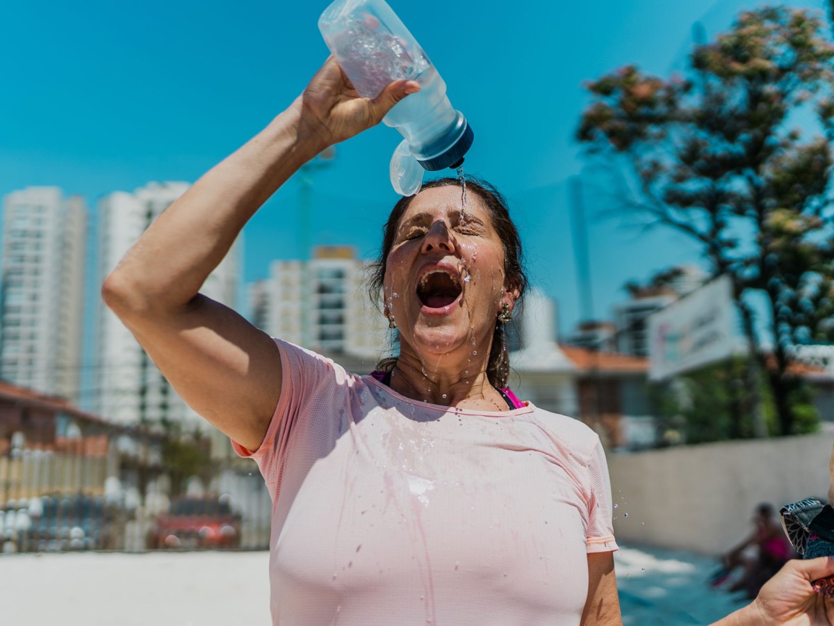 Frau, die sich mit einer Flasche Wasser abkühlt.