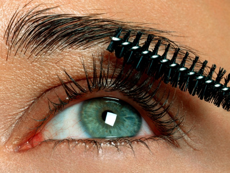 Nahaufnahme eines Auges mit Wimpern und einer Wimpernbürste