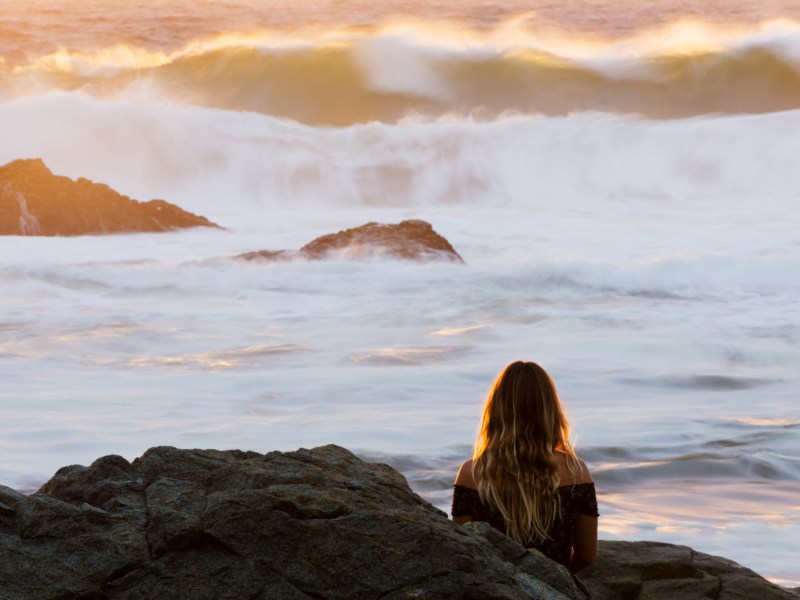 Frau sitzt nachdenklich am Meer