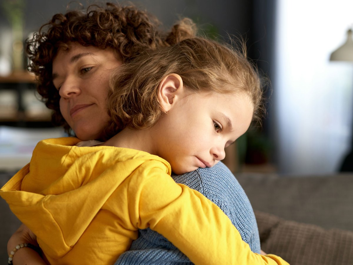 Mutter und Tochter umarmen sich. Das M&auml;dchen, ca. 10 Jahre, sieht traurig und entt&auml;uscht aus.