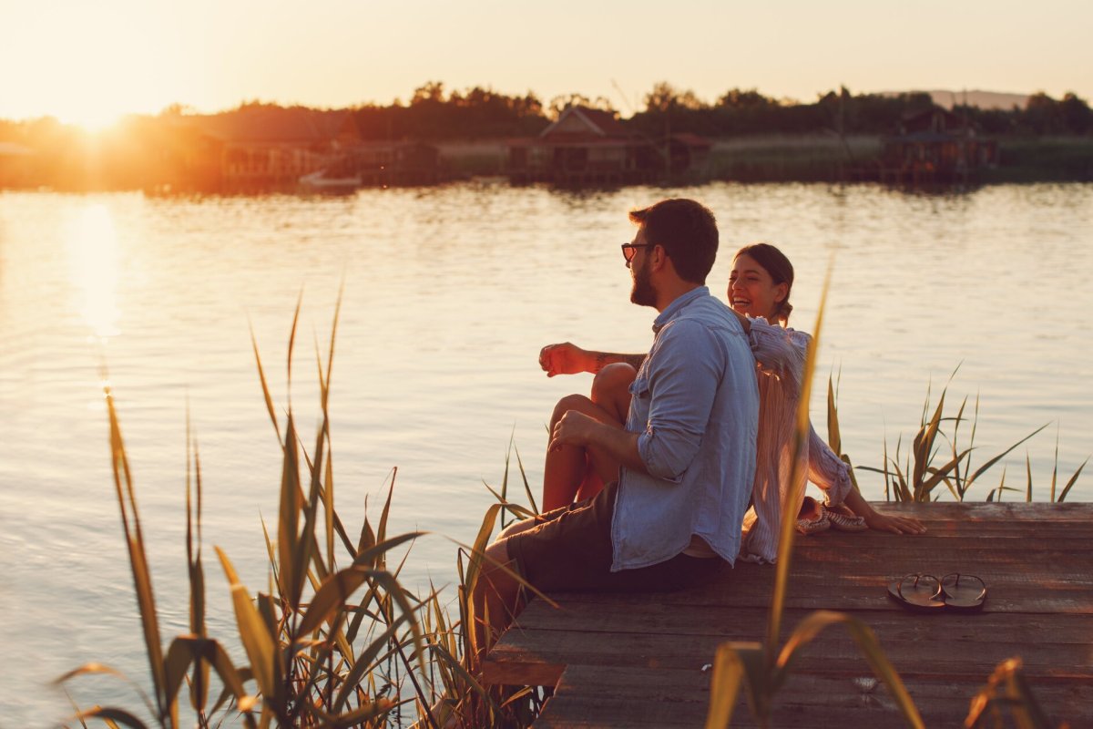 Frau und Mann am Steg am Lachen im Sonnenuntergang