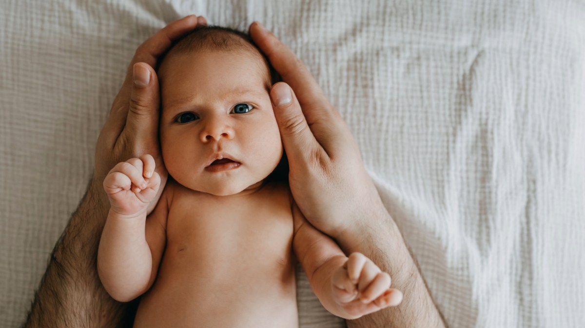 Babykopf in Hand von Erwachsenen