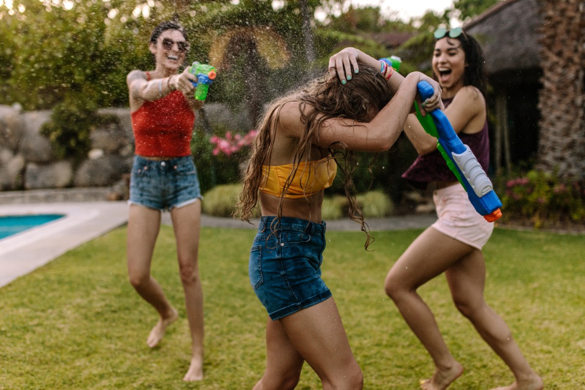 Drei Freundinnen machen eine Wasserschlacht im Garten