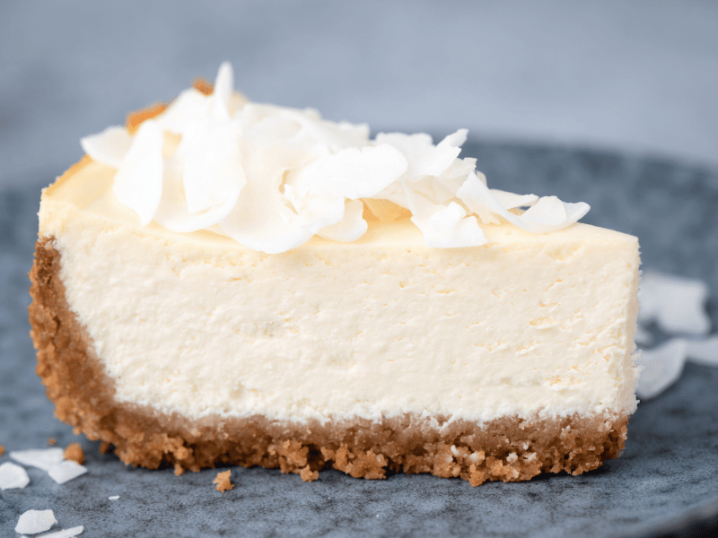 Käsekuchen mit Kokosraspeln auf einem blauen Teller.