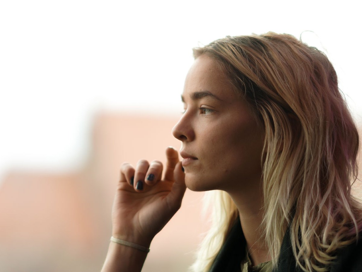 Frau blickt ernst aus dem Fenster
