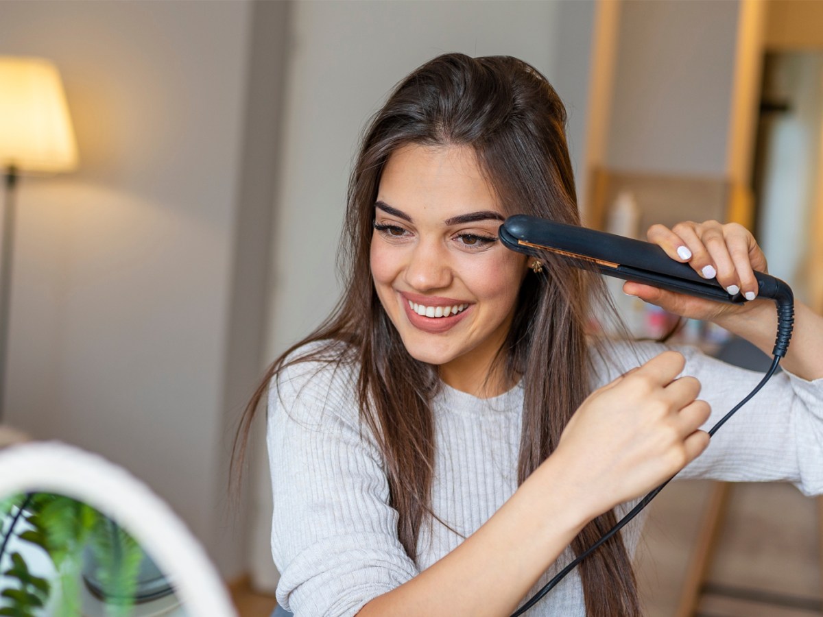 Frau beim Glätten ihrer langen Haare.