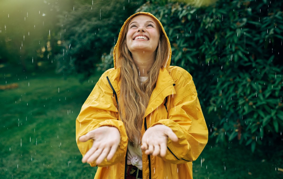 Frau genießt den Regen, während die Sonne scheint.