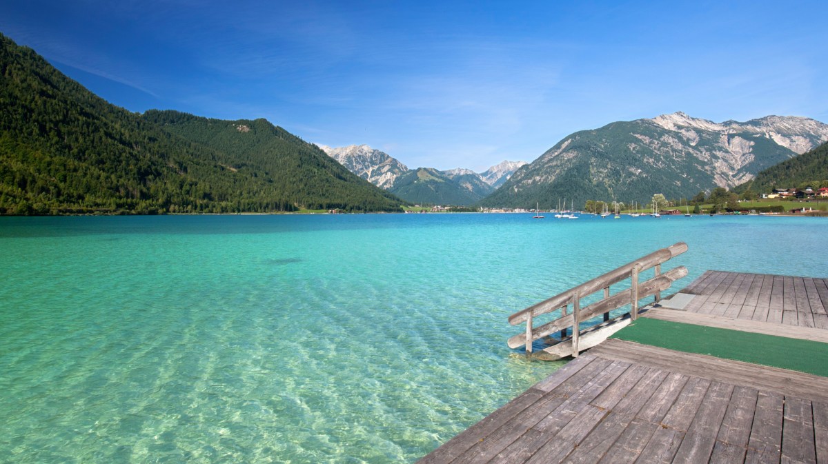 Badesee mit Steg umgeben von Bergen