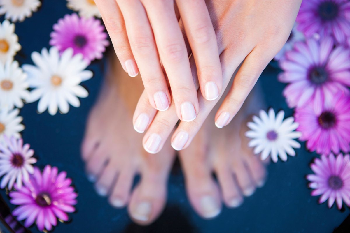 Gepflegte Hände und Füße in einem Wasserbad.