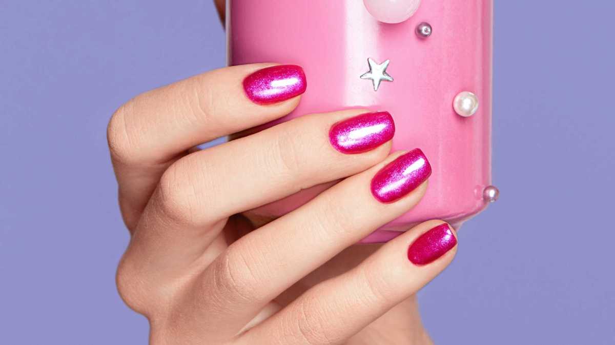 Pinke Nägel halten eine rosa Getränkedose fest