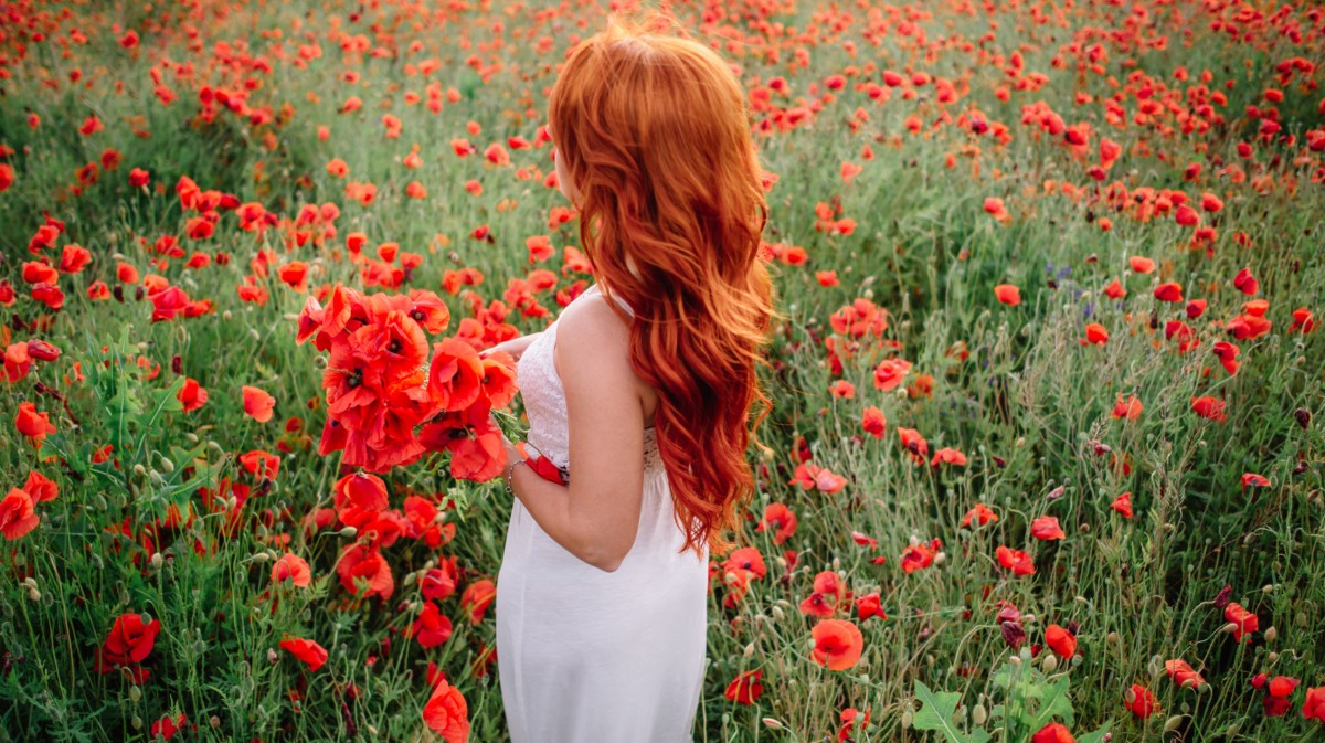 Frau mit roten Haaren steht in Feld.