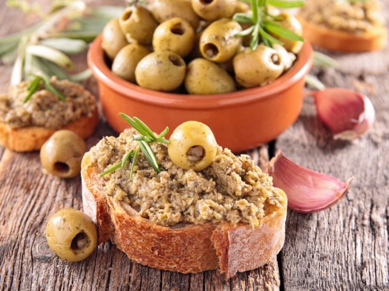 Grüne Oliven und Oliven-Tapenade auf Baguette.