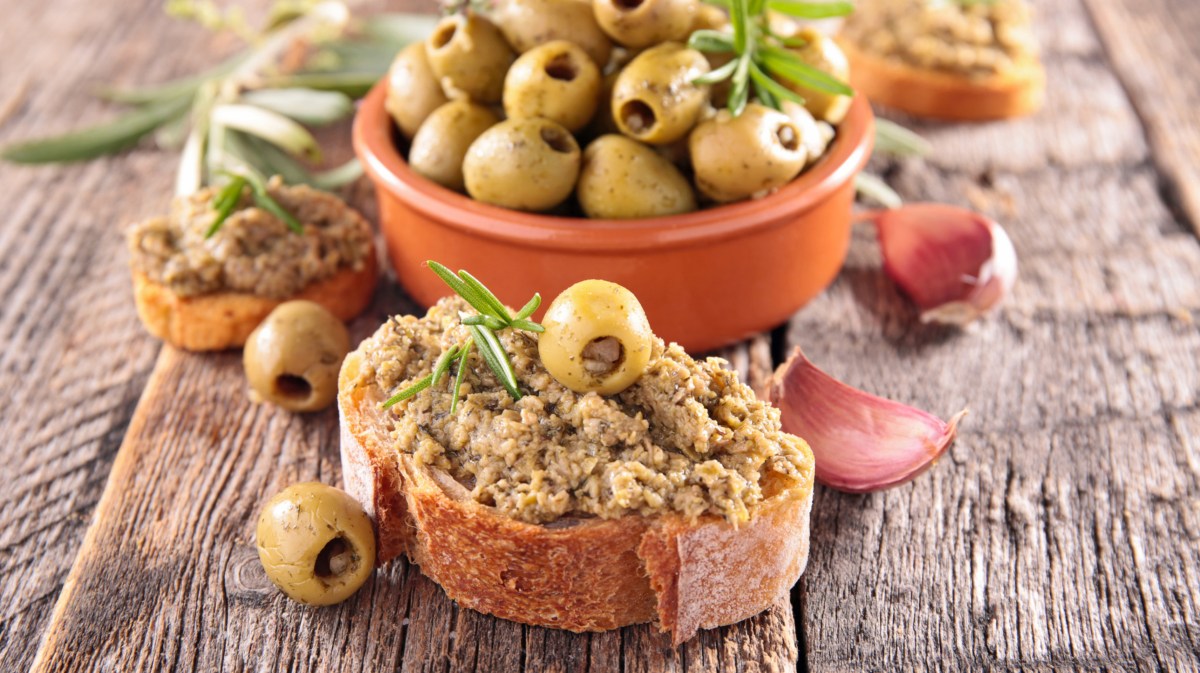 Grüne Oliven und Oliven-Tapenade auf Baguette.