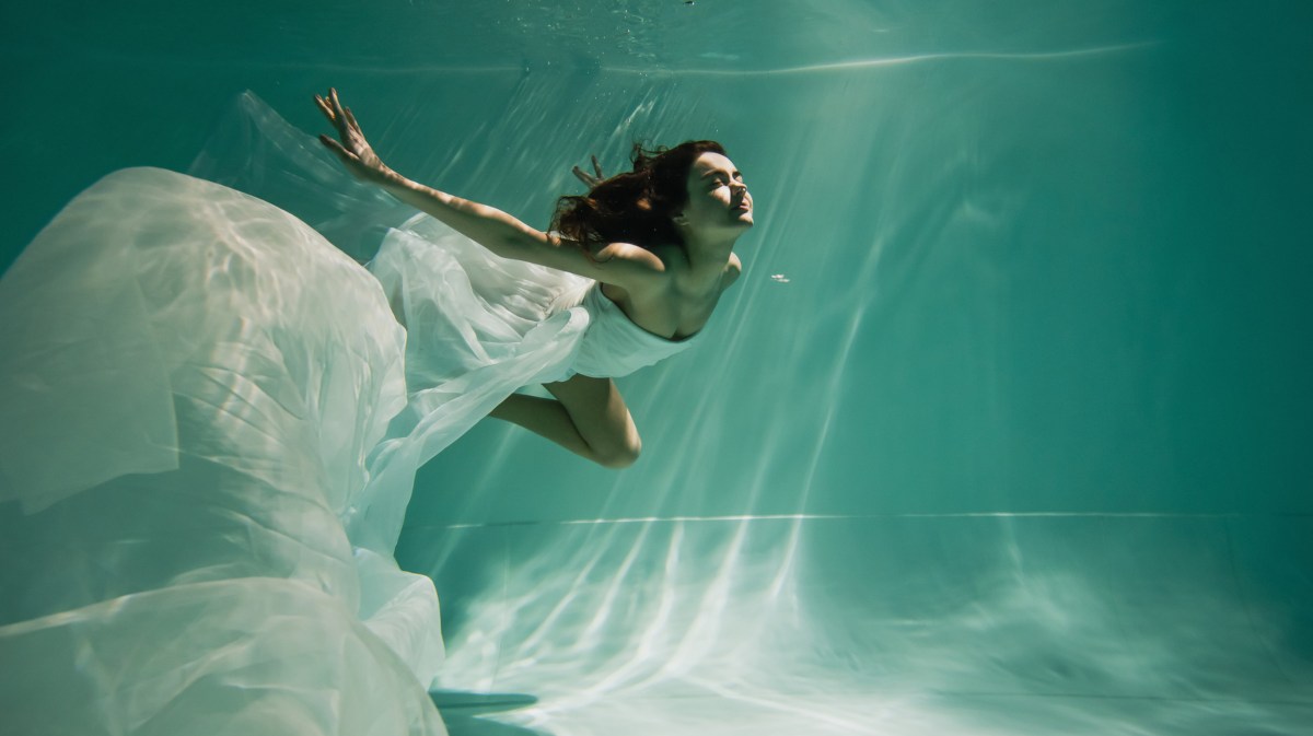 Frau schwimmt in weißem Kleid.