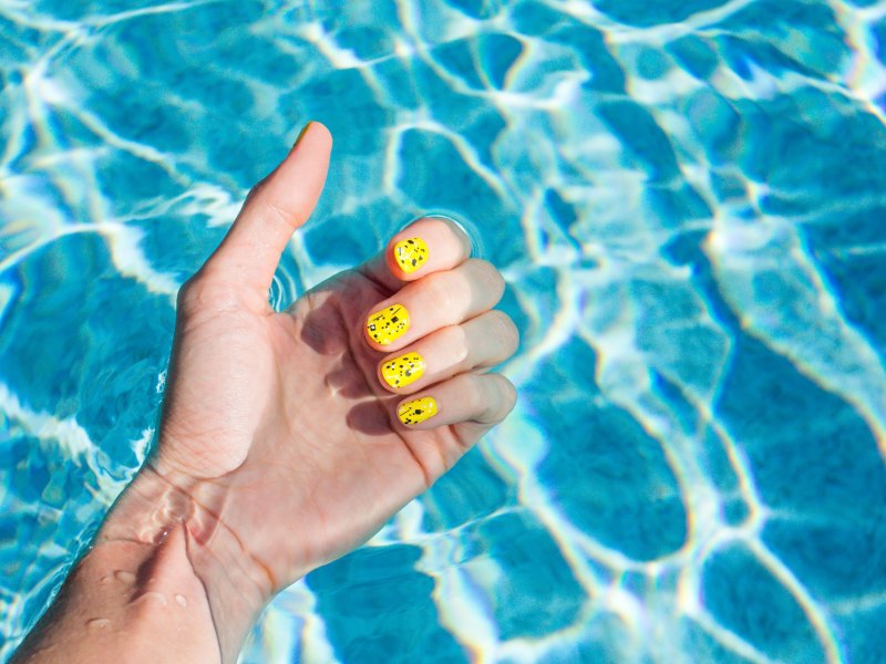 Frau mit lackierten Nägel im blauen Pool.