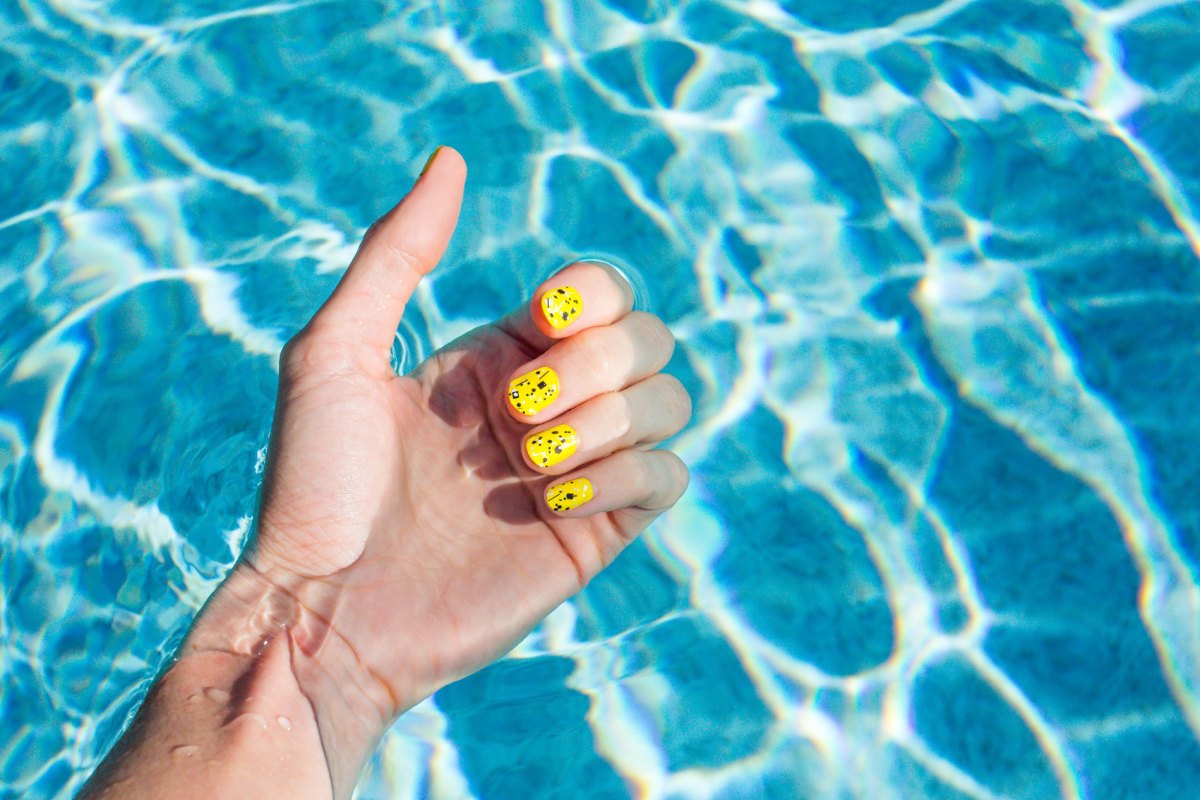 Frau mit lackierten Nägel im blauen Pool.