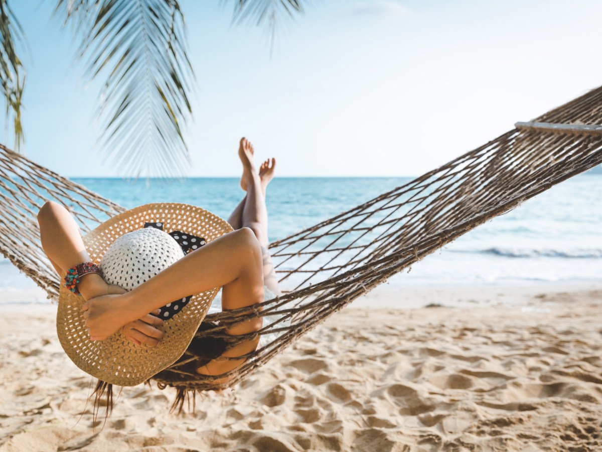 Frau liegt in einer Hängematte am Strand.