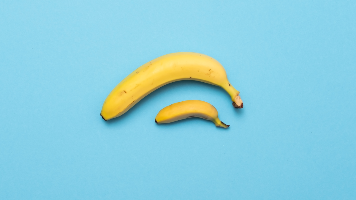 Eine große und eine kleine gelbe Banane liegen nebeneinander auf einem hellblauen Hintergrund.