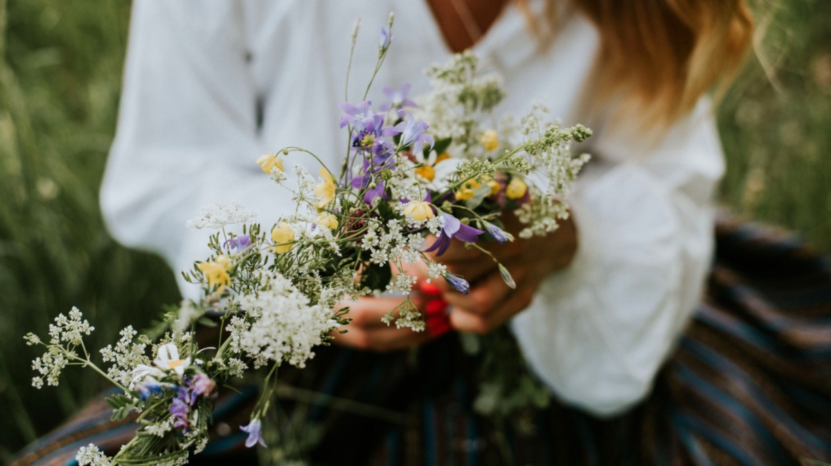 Frau mit weißer Blume hat Sommerblumen in der HAnd