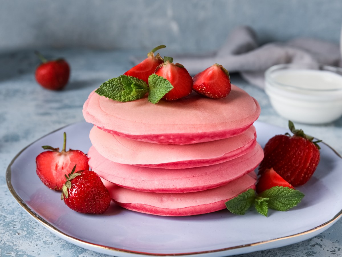 Pinke Pancakes mit Erdbeeren serviert auf einem Teller