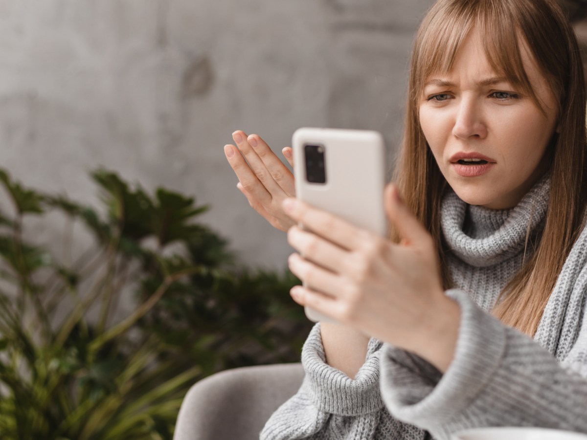Frau schaut w&uuml;tend auf ihr Handy.