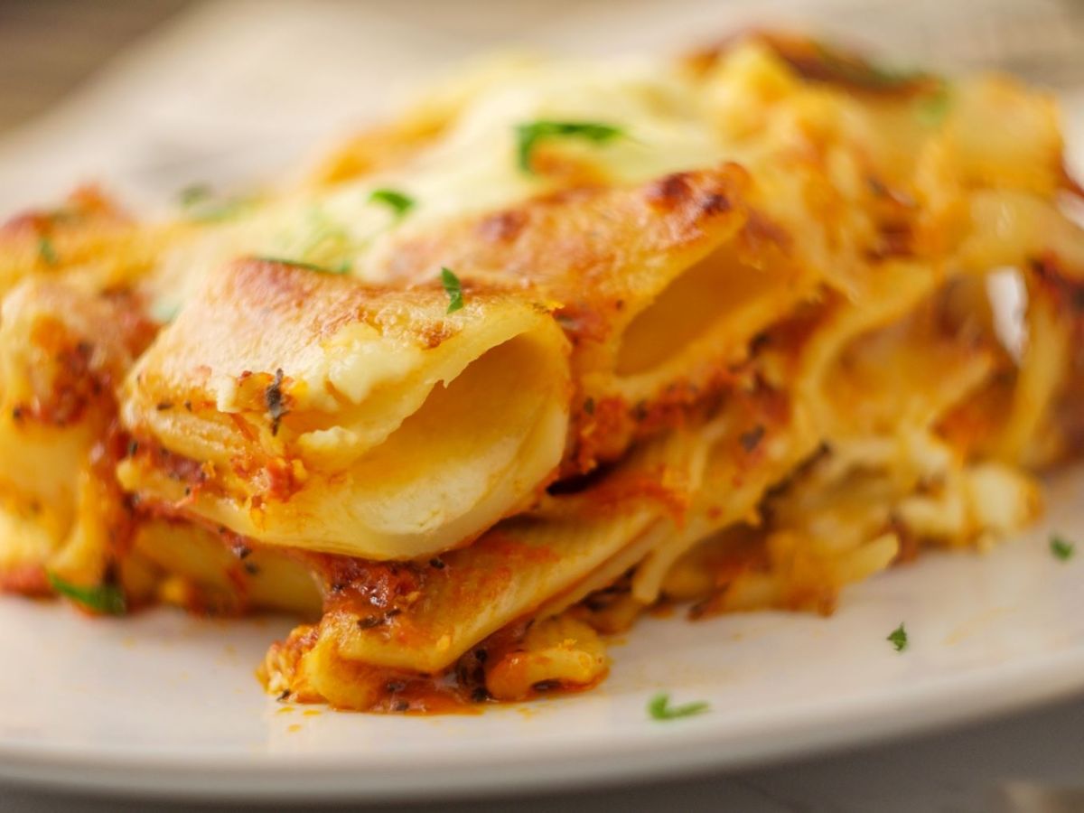 Ziti al forno mit frischen Kräutern auf weißem Pastateller. Frontalansicht.