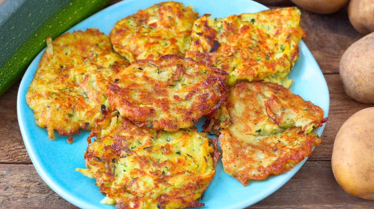 Rösti aus Kartoffeln und Zucchini auf einem blauen Teller.