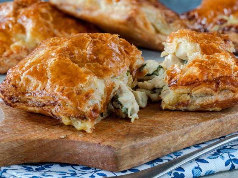 Blätterteig-Taschen mit Pilzen auf einem Holzbrett.