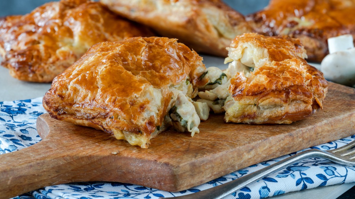 Blätterteig-Taschen mit Pilzen auf einem Holzbrett.