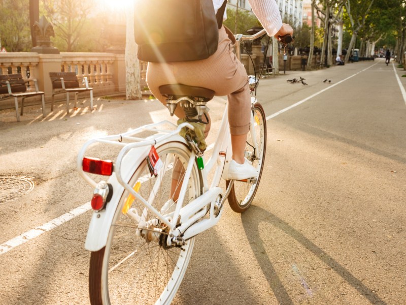 Mann auf einem Fahrrad, der im Sonnenlicht auf einem Fahrradweg fährt