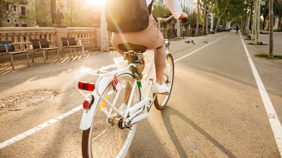 Mann auf einem Fahrrad, der im Sonnenlicht auf einem Fahrradweg fährt