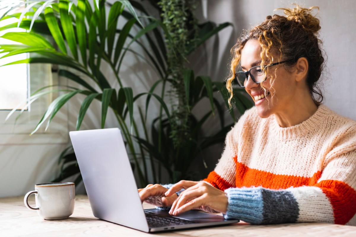 Frau sitzt am Schreibtisch mit ihrem Laptop.