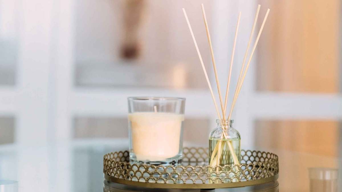 Kerze und Duftstäbchen auf einem Tablett.