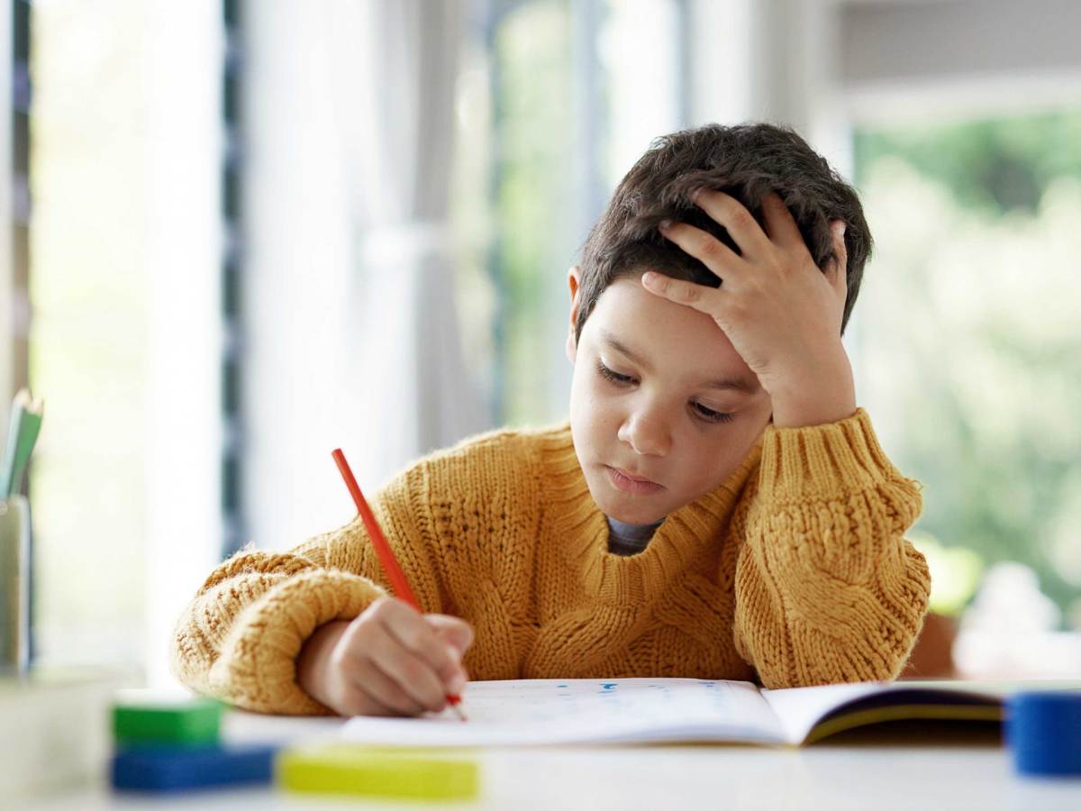 Junge sitzt nachdenklich und konzentriert an seinen Schulaufgaben.