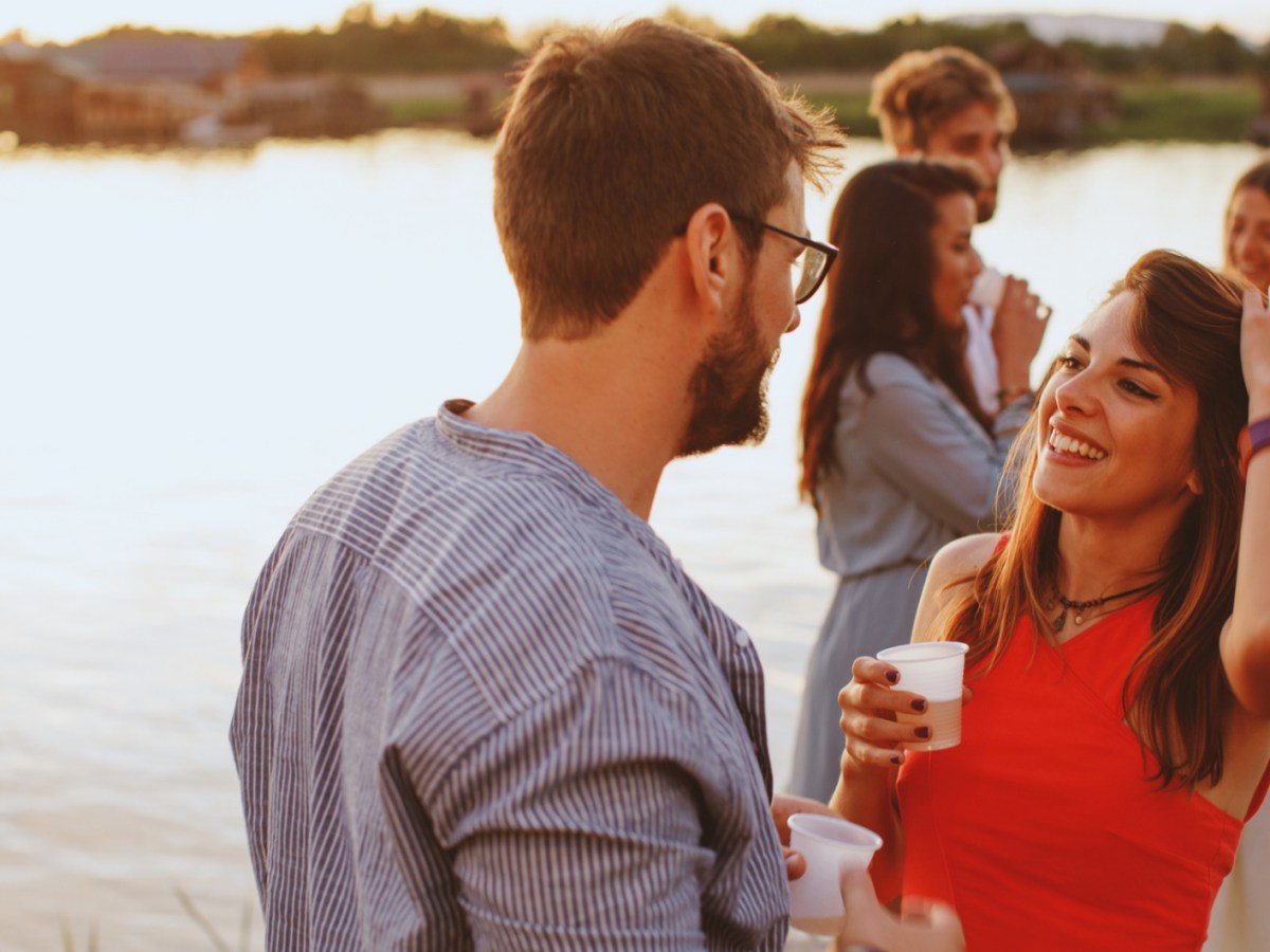 Frau und Mann auf einem Steg, die sich anlachen und miteinander flirten