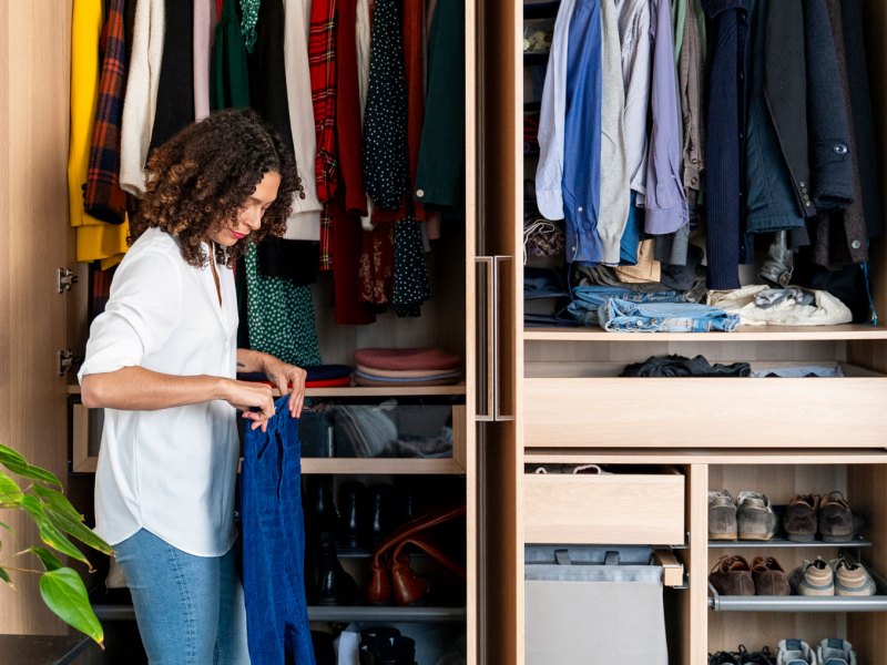 Frau steht vor Kleiderschrank und hat Jeans in den Händen