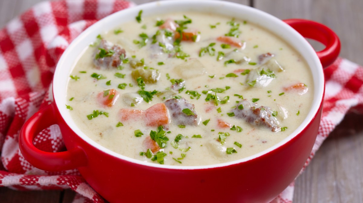 Cremige Hackfleisch-Kohlrabi Suppe in einer roten Suppenschüssel.