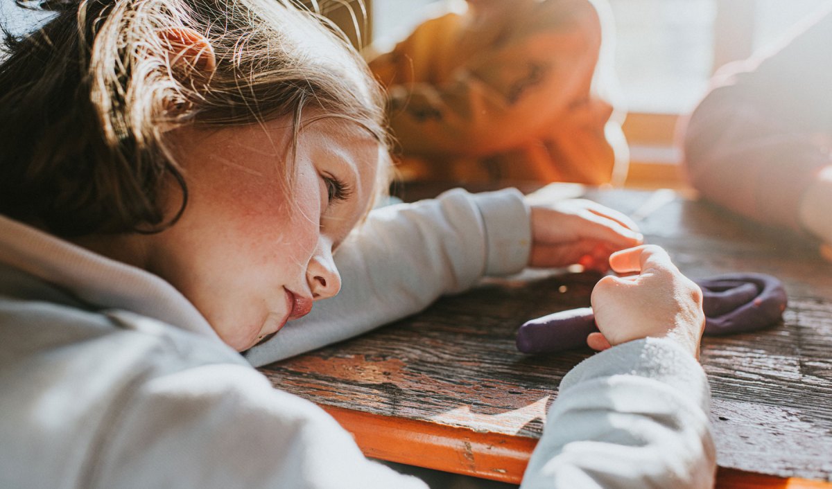 Kind hat Kopf auf Tisch gelegt und schaut traurig