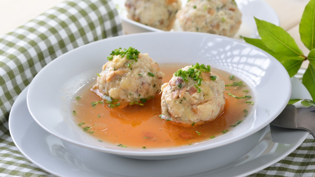 Tiroler Speckknödelsuppe in weißem Suppenteller.