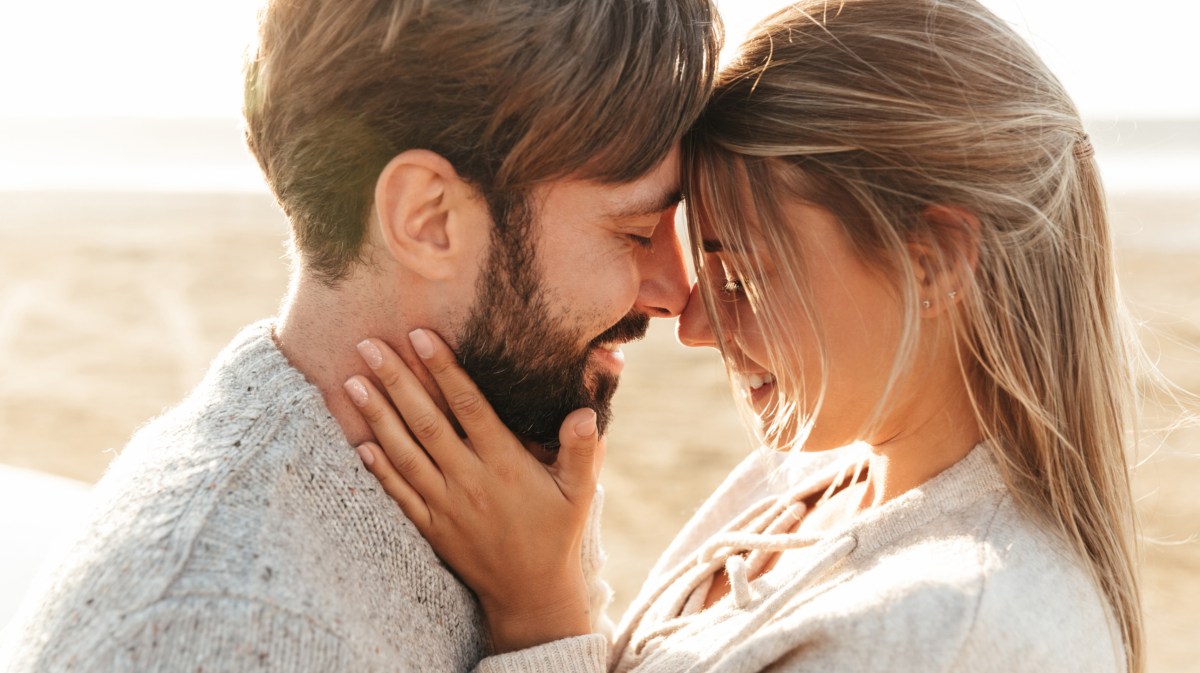 Frau und Mann sind am Strand und schauen sich tief in die Augen.