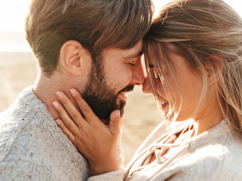 Frau und Mann sind am Strand und schauen sich tief in die Augen.