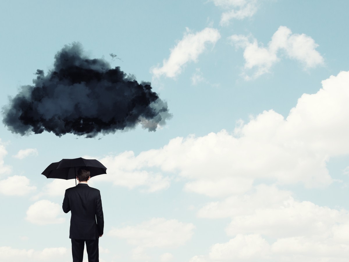 Mensch mit Regenschirm darüber dunkle Wolke