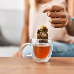 Eine Frau zieht einen Teebeutel aus einer Teetasse.