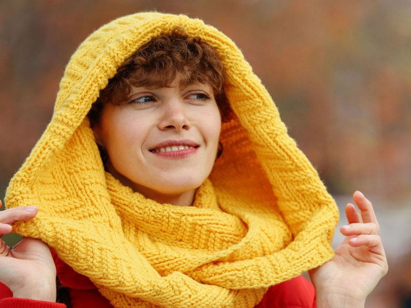 Frau mit warmen Schal beim Herbstspaziergang.