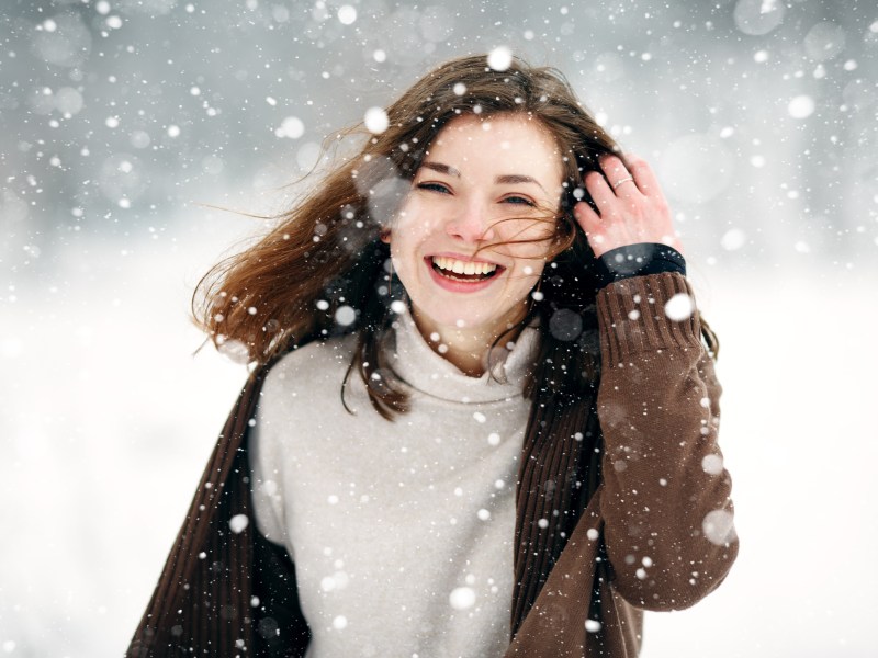 Frau mit braunen Haaren im Schnee.