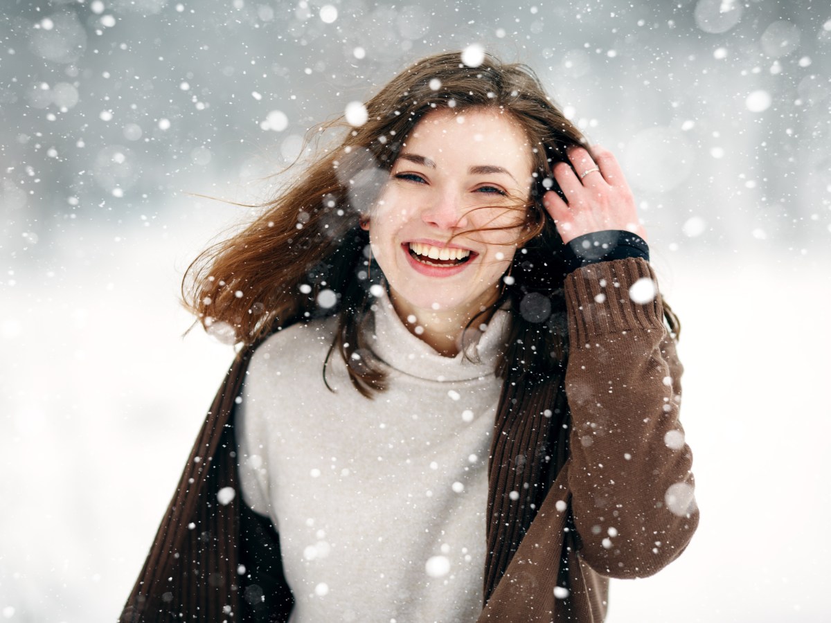 Frau mit braunen Haaren im Schnee.