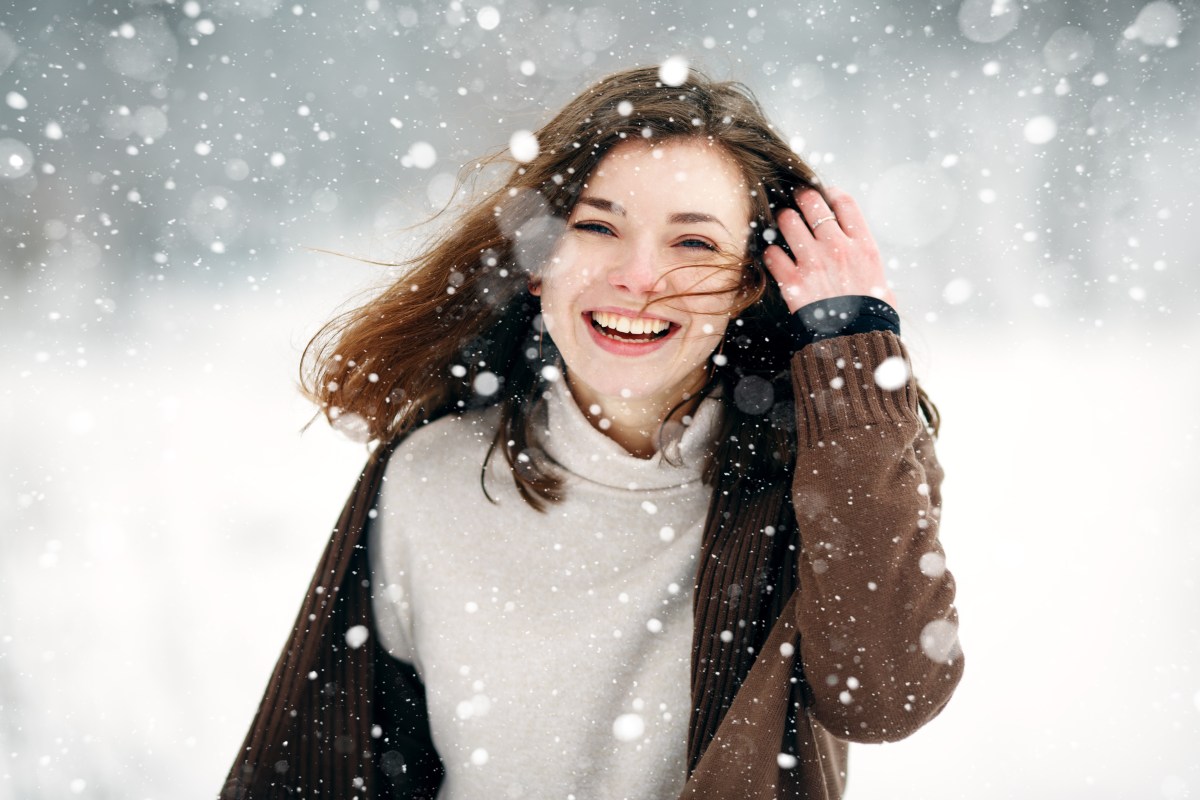 Frau mit braunen Haaren im Schnee.