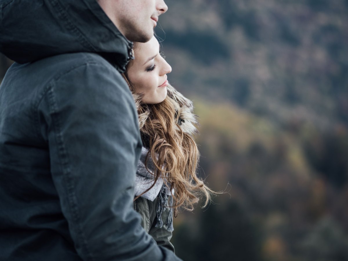 Mann und Frau stehen Arm in Arm auf einem Berg.